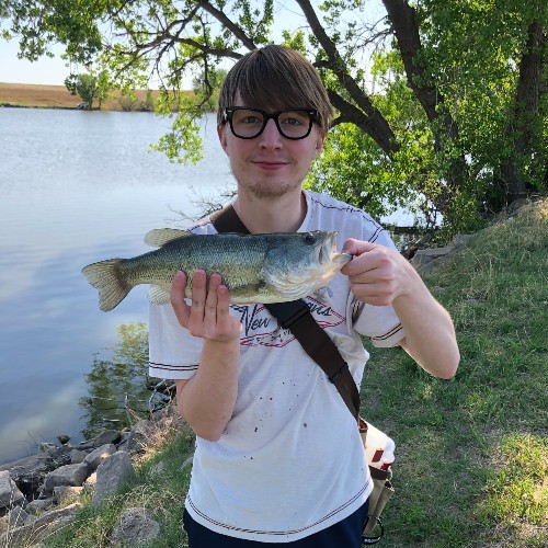 me holding a fish in front of a lake